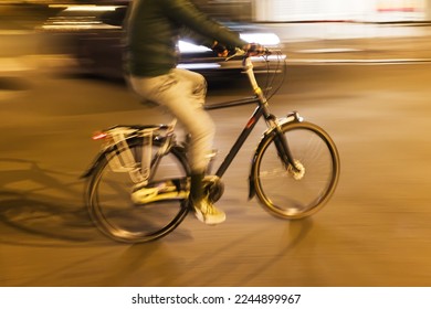 picture with intentional motion blur effect of a bicycle rider on a city street at night