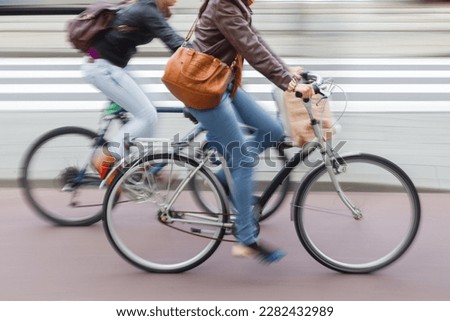 picture with intentional motion blur of young women with shopping bags riding bicycle on a city street
