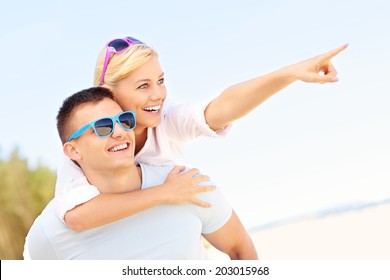 A Picture Of A Joyful Couple Pointing To The Sky At The Beach