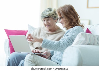 Picture of kind carer teaching old lady to use laptop