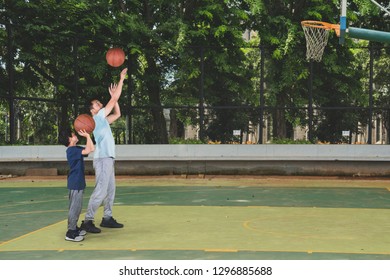 Picture Of Little Boy Learning To Shoot A Basketball With His Father While Exercising In The Court