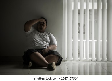 Picture of a lonely fat man crying in the dark room and sitting near the window 