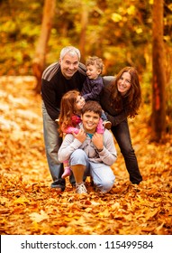 Picture Of Lovely Family In Autumn Park, Young Parents With Nice Adorable Kids Playing Outdoors, Five Cheerful Person Have Fun On Backyard In Fall, Happy Family Enjoy Autumnal Nature