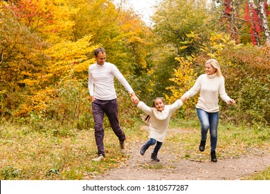 Picture Of Lovely Family In Autumn Park, Young Parents With Nice Adorable Daughter Playing Outdoors, Have Fun On Backyard In Fall, Happy Family Enjoy Autumnal Nature