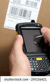 Picture Of Male Hands Using A Hand Held Barcode Scanner Enterprise Digital Assistant Computer To Take Inventory With A UPC Box Label.