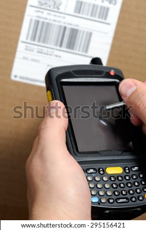 Picture of male hands using a hand held barcode scanner Enterprise Digital Assistant computer to take inventory with a UPC box label.