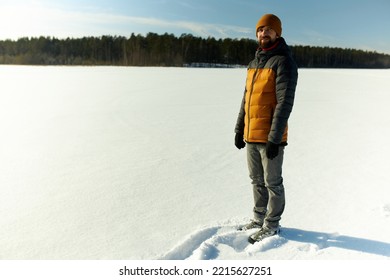 Picture Of Male Tourist In Warm Puffer And Hat, Wearing Boots For Winter Hiking, Standing In Small Snow Draft With Copy Space On The Left. Beauty Of Wild Snowy Nature. Exploring New Spots