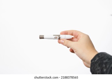 Picture of a man hand holding a lancet for checking blood sugar level by glucose meter on white background, diabetes monitoring concept.