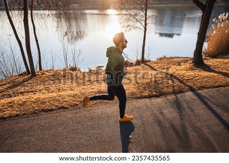 Picture of man running in park during sunny autumn afternoon