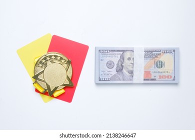 A picture of medal on yellow and red card with fake cash insight. Match fixing and sports bribery concept.