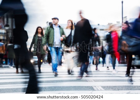 picture with motion blur of a crowd of people crossing a city street at the pedestrian crossing