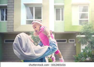 Picture Of Muslim Woman Playing And Lifting Her Adorable Baby While Standing At Outdoors