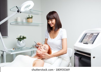 picture of nice beautician doing oxygen therapy for young woman laying down with closed eyes in a beauty salon
