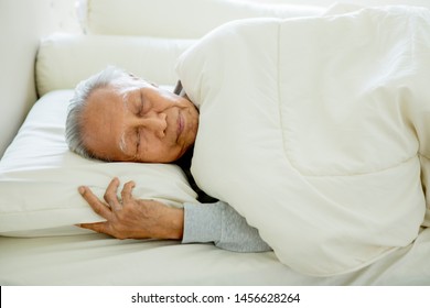 Picture of old man sleeping well on the comfortable bed with blanket. Shot at home