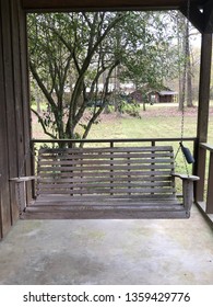 A Picture Of An Old Wooden Swing In A Front Porch Of A House With Background Of Trees And Green Grass In The Yard. It Looks Sad And Empty With Nobody Around. There Are Spaces For Inserting Texts.