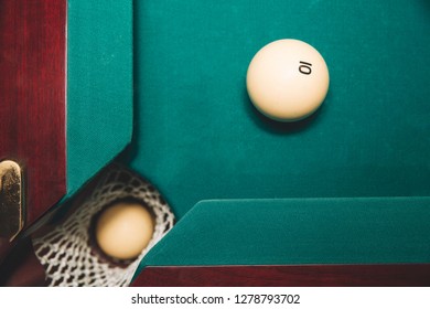 Picture Of One Billiard Ball In Billiard Hole. Another One Is On Green Bed Of Table Close To Hole. Number 10 Is On It.