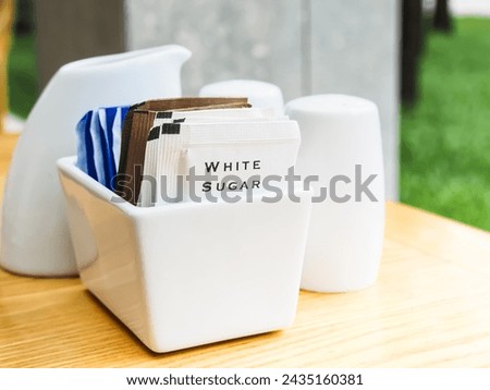 Picture of packets of white sugar placed in a white container.