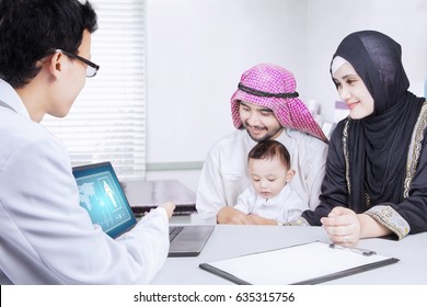 Picture Of Pediatrician Showing A Medical Report To Muslim Family On A Laptop While Sitting In The Clinic