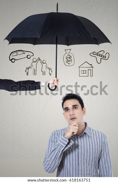 Picture of a pensive young man imagining\
her wish under umbrella. dreams insured\
concept
