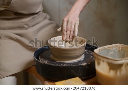 Similar – Young female sitting by table and making clay or ceramic mug