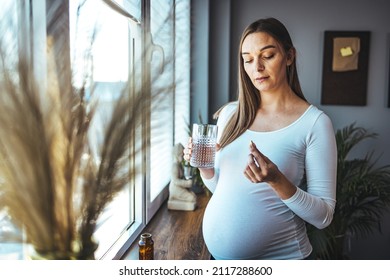 Picture Of Pregnant Woman Taking Medication Pills. Pregnant Woman Taking Pill Against Heartburn. A Young Pregnant Woman Is Taking Medications And Drinking Water.