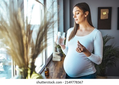 Picture Of Pregnant Woman Taking Medication Pills. Pregnant Woman Taking Pill Against Heartburn. A Young Pregnant Woman Is Taking Medications And Drinking Water.