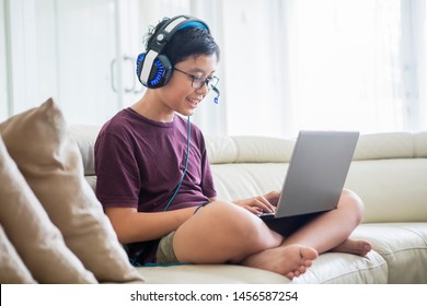 Picture of preteen boy using a laptop for playing online games and wearing headphone at home