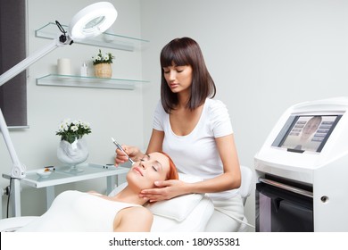 picture of pretty beautician doing microdermabrasion procedure for young woman laying down with closed eyes in a beauty salon
