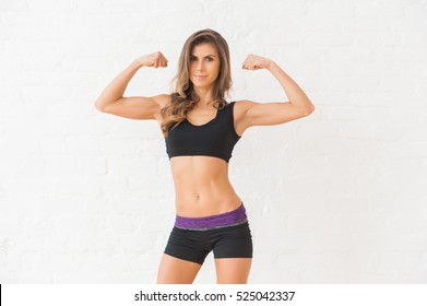 Picture of a pretty sportswoman showing her biceps isolated on white background