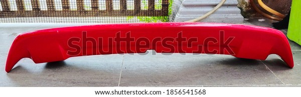 A\
picture of red car spoiler in horizontal\
position.