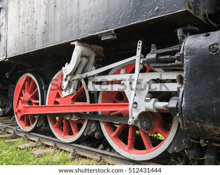 Picture of the red steam locomotive wheels and rods closeup.