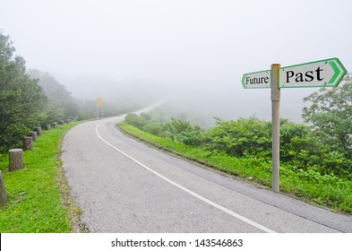 A picture of a road leading into a misty area with a signpost showing the word future and past. Future and Past concept.