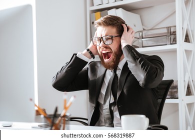 Picture of screaming bearded businessman sitting in office while looking aside.