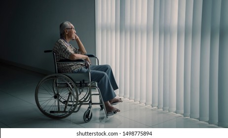 Picture of senior man sitting in the wheelchair while looking out the window in the retirement home