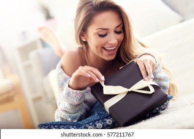 Picture Showing Woman Opening Present On Carpet