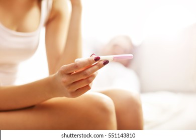 Picture showing woman with pregnancy test in bedroom