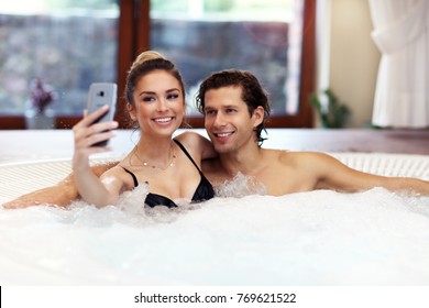Picture showing young couple enjoying jacuzzi in hotel spa