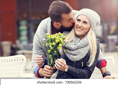 Imagen que muestra a una pareja joven con flores saliendo en la ciudad