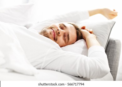Picture showing young man stretching in bed