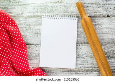 The picture shows an open notepad with a pen, napkin and rolling pin on the wooden table. top view. copy space - Powered by Shutterstock