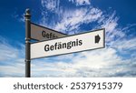 The picture shows a signpost and a sign that points in the direction of the prison in German.