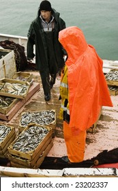 Picture Shows Two Fishermen On A Trawler Boat On A Rainy Winter Day