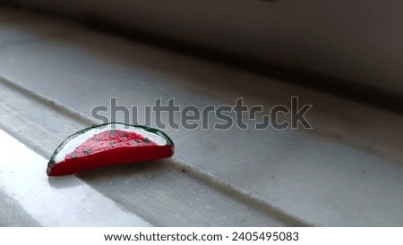 Picture of the small pin is in the shape of a watermelon slice which symbolizes Palestine being illuminated by light