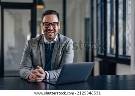 Picture of smiling adult man, loving working from the office.