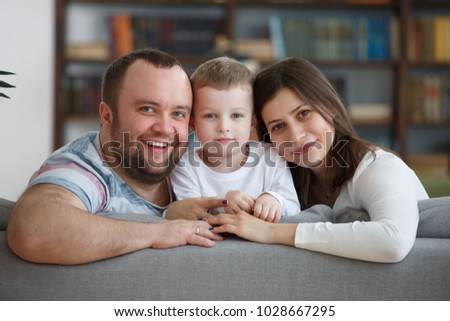 Picture of smiling family with son sitting on gray sofa