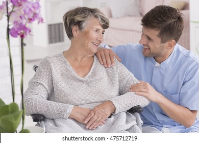 Picture Of A Smiling Senior Woman And Her Male Caregiver, Light Interior