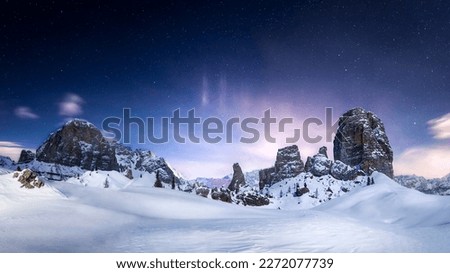 Picture of a starry night over the Cinque Torri on a snowy winter landscape in Cortina d'Ampezzo, Italy