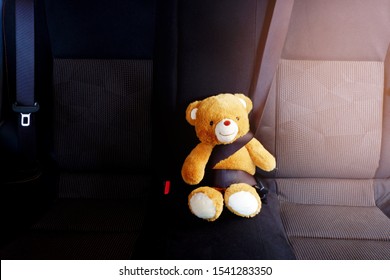 The picture of a teddy bear is fastened with a seat belt in the car to show the safety of children using the car. - Powered by Shutterstock