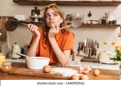 Picture of a thoughtful confused sad young blonde girl chef cooking at the kitchen thinking.