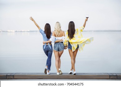A picture of three young happy women in the summer. The view from the back.